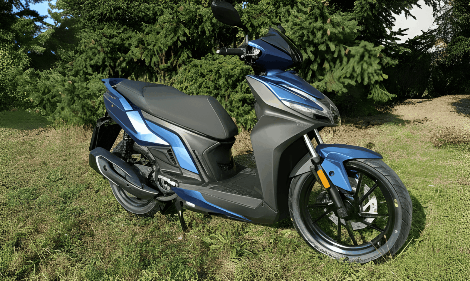 Vozidlo autoškoly - skútr Kymco na trávníku u autoškoly