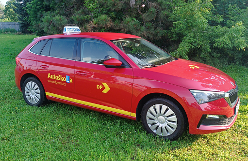 Vozidlo autoškoly - červená Scala na trávníku u autoškoly