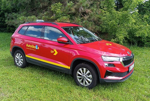 Vozidlo autoškoly - červený Karoq na trávníku u autoškoly