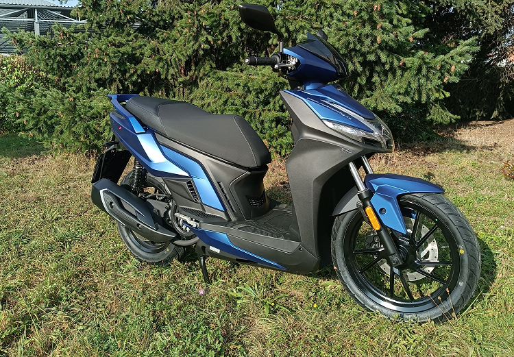 Vozidlo autoškoly - skútr Kymco na trávníku u autoškoly
