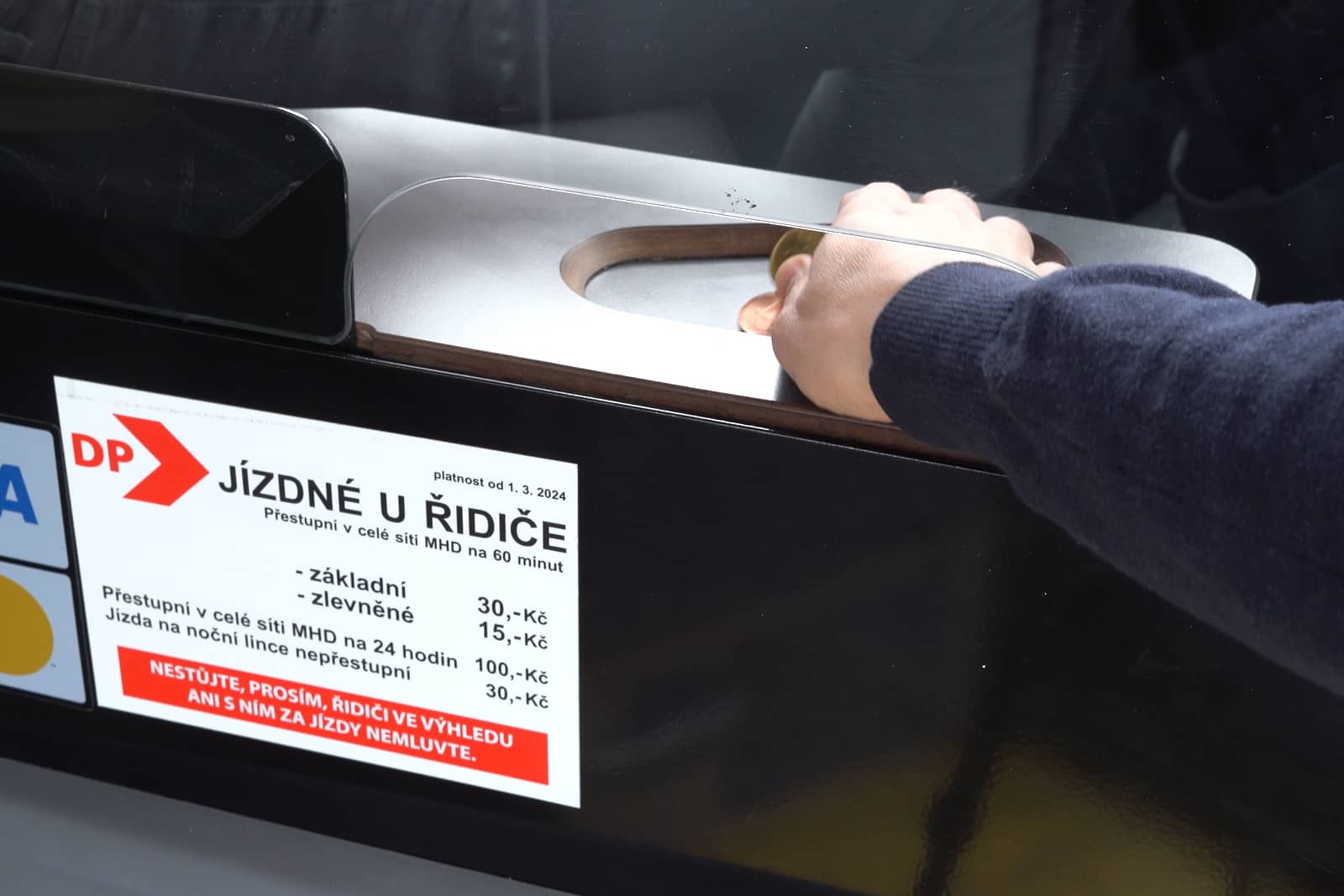 Ruka cestujícího dává řidiči drobné peníze při koupi jízdenky