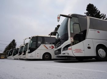 V zimě vedle sebe zaparkované autobusy zájezdové dopravy v areálu dopravního podniku